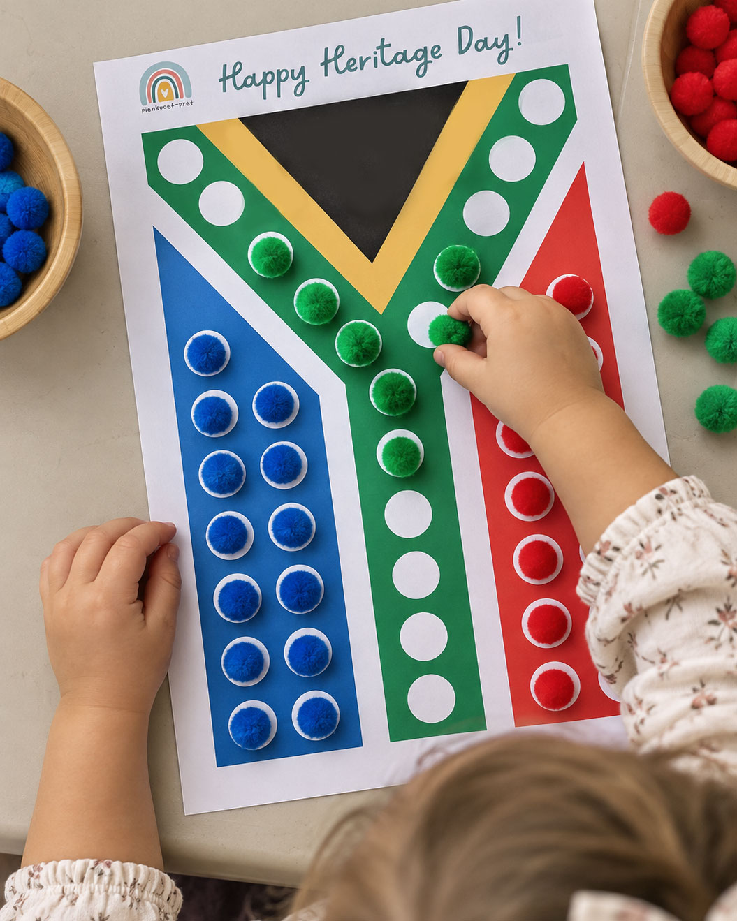 Kind pas pompons by kolletjies om 'n Suid-Afrikaanse vlag te bou